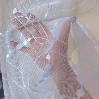 Zbliżenie przejrzystej siatki i wzoru kulek na firance żakardowej