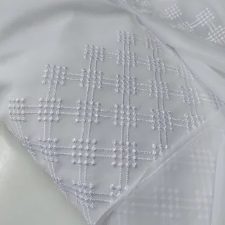 Biała firanka z krzyżykowym wzorem na szarym tle